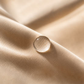Goutte transparente sur tissu de soie champagne — douceur de la formule